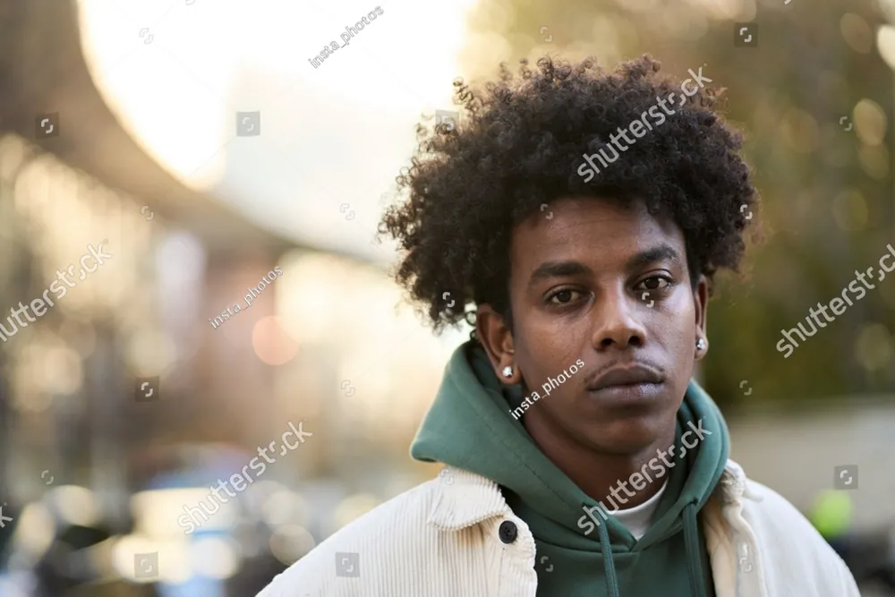 A teenager in a green hoodie looking straight ahead